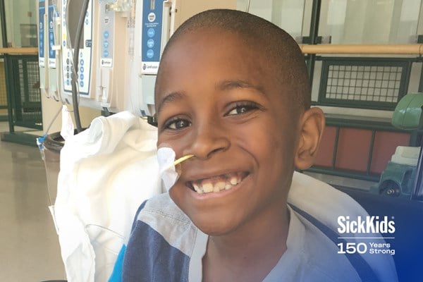 Young patient smiling brightly during medical procedure at SickKids Hospital, celebrating 150 years of pediatric care and healing.RetryClaude can make mistakes. Please double-check responses.