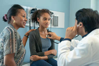 A doctor listens to a young girl's breathing.