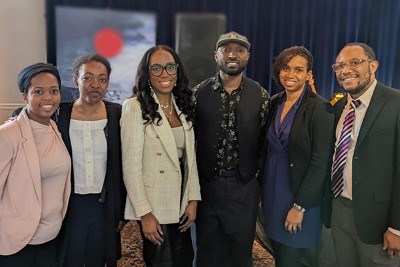 Six Black staff members standing together posing for a group photo.