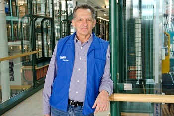 Volunteer Craig smiling for his photo beside SickKids elevators