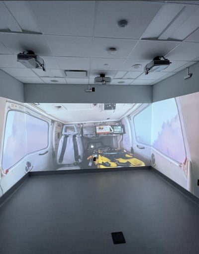 A room with projectors projecting a scene inside an ambulance on the three walls of the room.