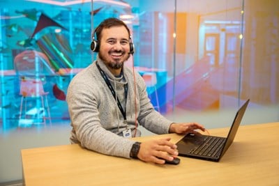 Man in front of a laptop wearing a headset.