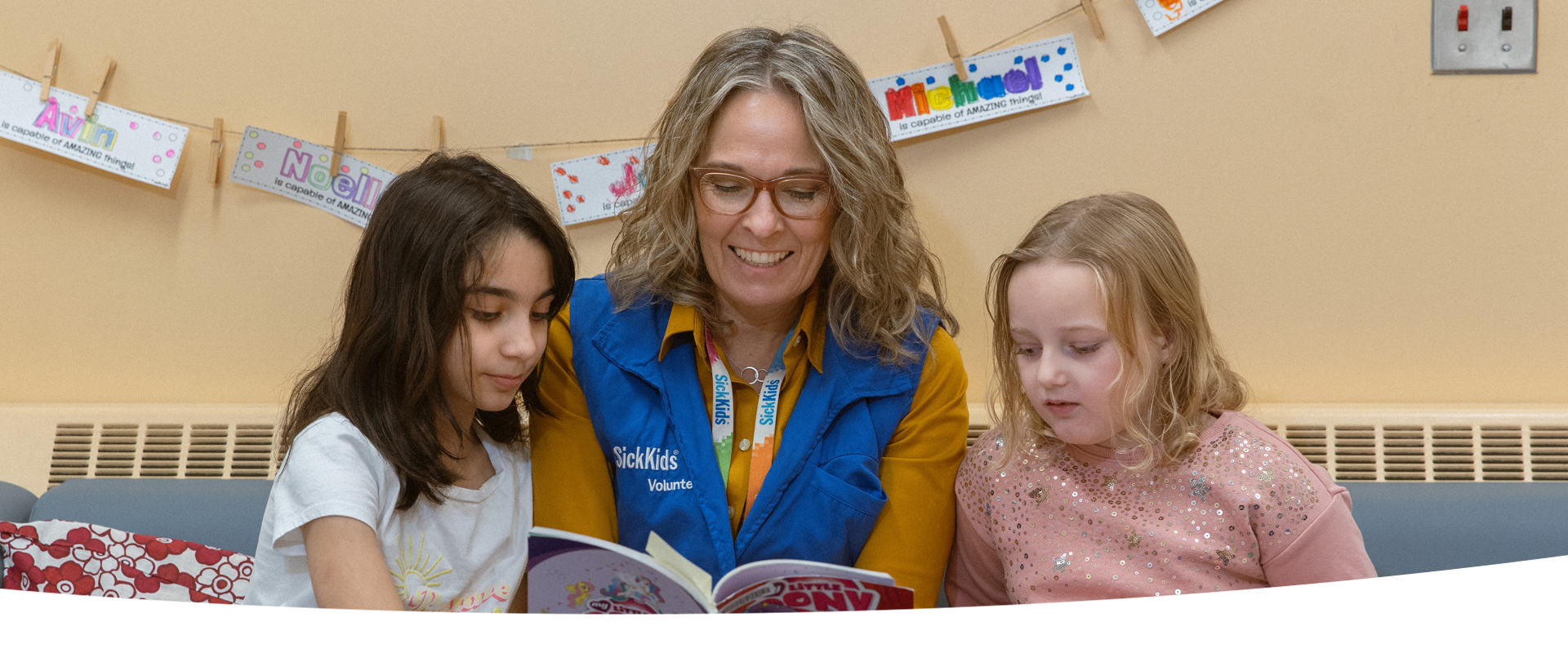 Volunteer reads a book to two children.