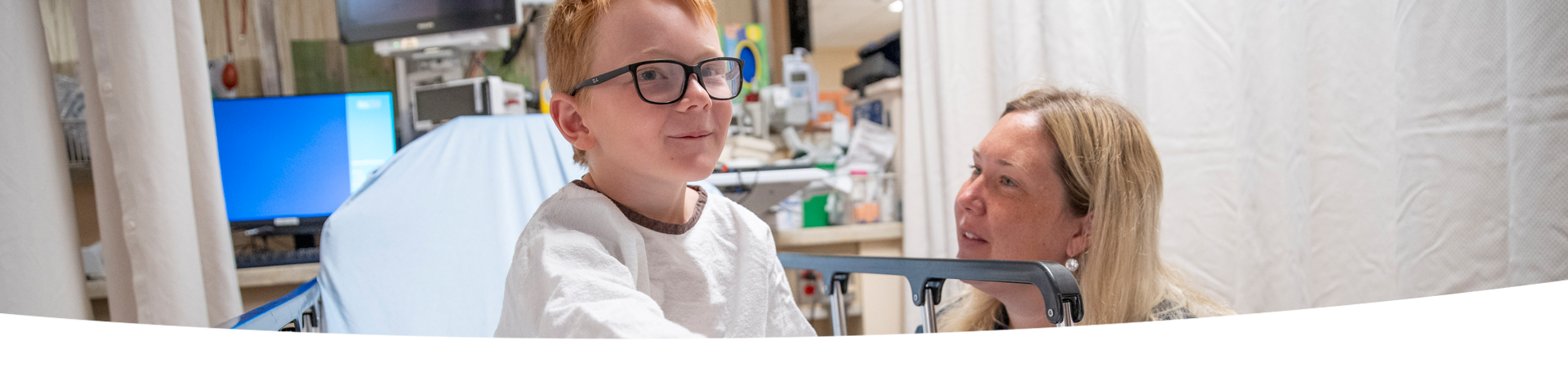 Child sits on a surgical bed, accompanied by an adult.